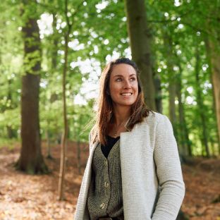 Junge Frau lächelt während sie im Wald spazieren geht