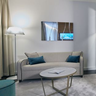 Das Patientenzimmer (Junior Suite) in der Blomenburg Privatklinik verfügt über einen großzügigen Eingangs- und Aufenthaltsbereich mit Couch.