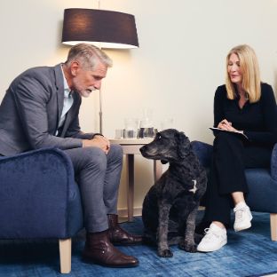 Patient, Ärztin und Therapiehund sitzen gemeinsam in der Therapie