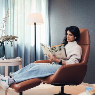 Patientin legt entspannt im Ruhebereich die Beine hoch und ließt ein Buch