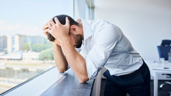 Angst vor der Arbeit - Stress Ein Mann stützt gestresst den Kopf auf die Hände
