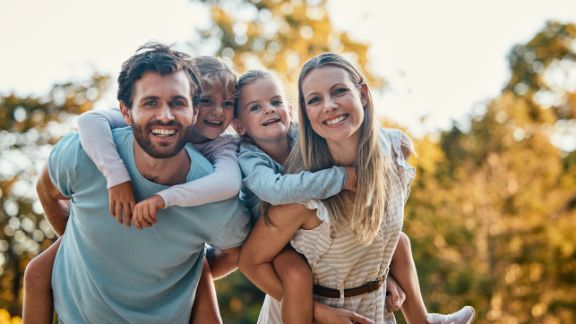 Glückliche 4-köpfige Familie lacht in die Kamera