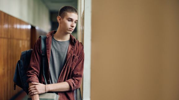 Einsamer Teenager steht traurig in der Schule