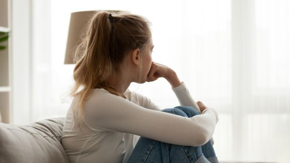 Kinder und Jugendambulanz der Blomenburg Trauriges Mädchen sitzt am Fenster