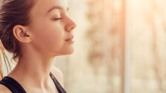Entspannte Frau atmet tief ein und aus Die Blomenburg Privatklinik wendet das Prinzip der Achtsamkeit als Adjuvante Therapie an.