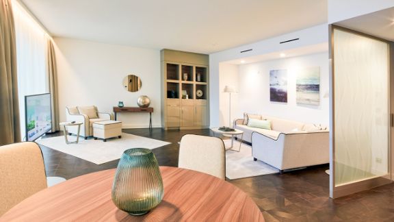 Raumansicht der Luxury Suite mit Tisch, gemütlichem Sofa und Flachbildschirm