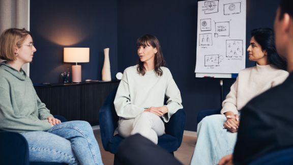 Gruppentherapie in der Blomenburg Frankfurt Patientengruppe sitzen im Stuhlkreis mit Therapeutin zusammen
