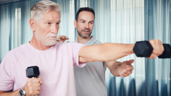 Sporttherapie in der Blomenburg Frankfurt Patient trainiert mit Sporttherapeut zusammen an Kurzhanteln