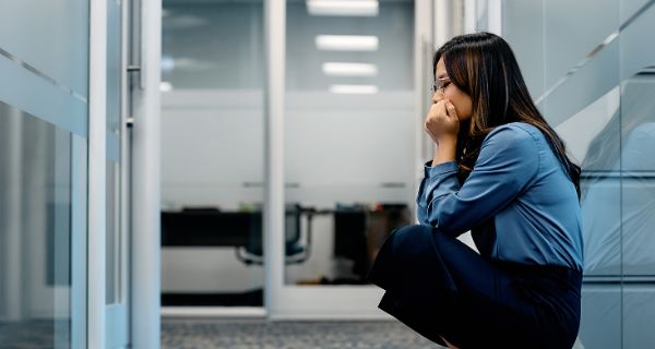 Angst vor der Arbeit - Panikattacke im Büro Junge Frau sitzt auf dem Boden um Büro und hat eine Panikattacke
