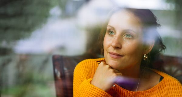 Dame blick entspannt aus dem Fenster. Ihr Umgebung spiegelt sich im Glas