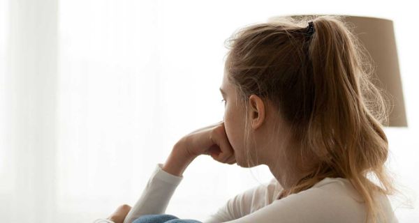 Mädchen sitzt am Fenster und schaut in die Ferne Kinder- und Jugendlichenpsychotherapie in Hamburg im Fachzentrum Falkenried