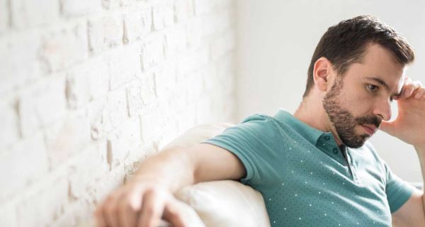 Mann auf der Couch grübelt und denkt nach Interview mit Professor Stephan Ahrens vom Fachzentrum Falkenried zum Stress Begriff