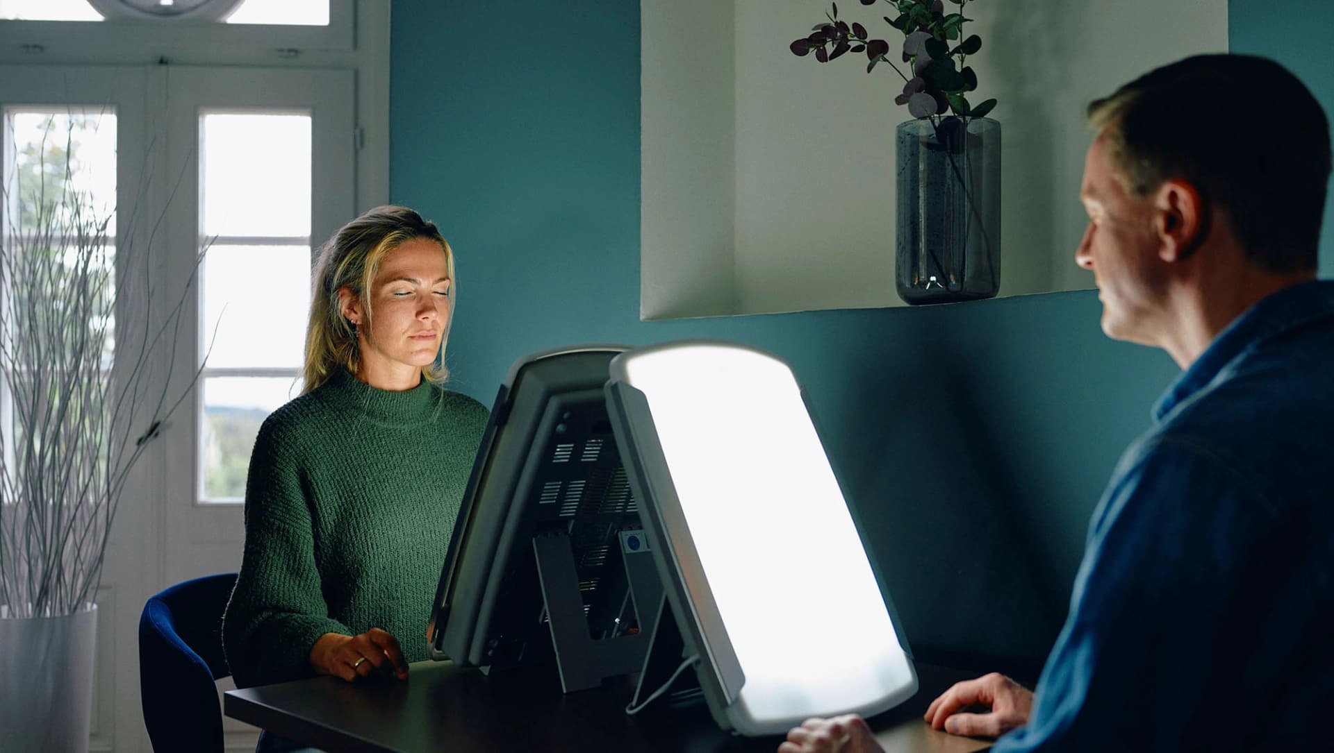 Patienten sitzen mit geschlossenen Augen vor Sonnenlicht-Lampe