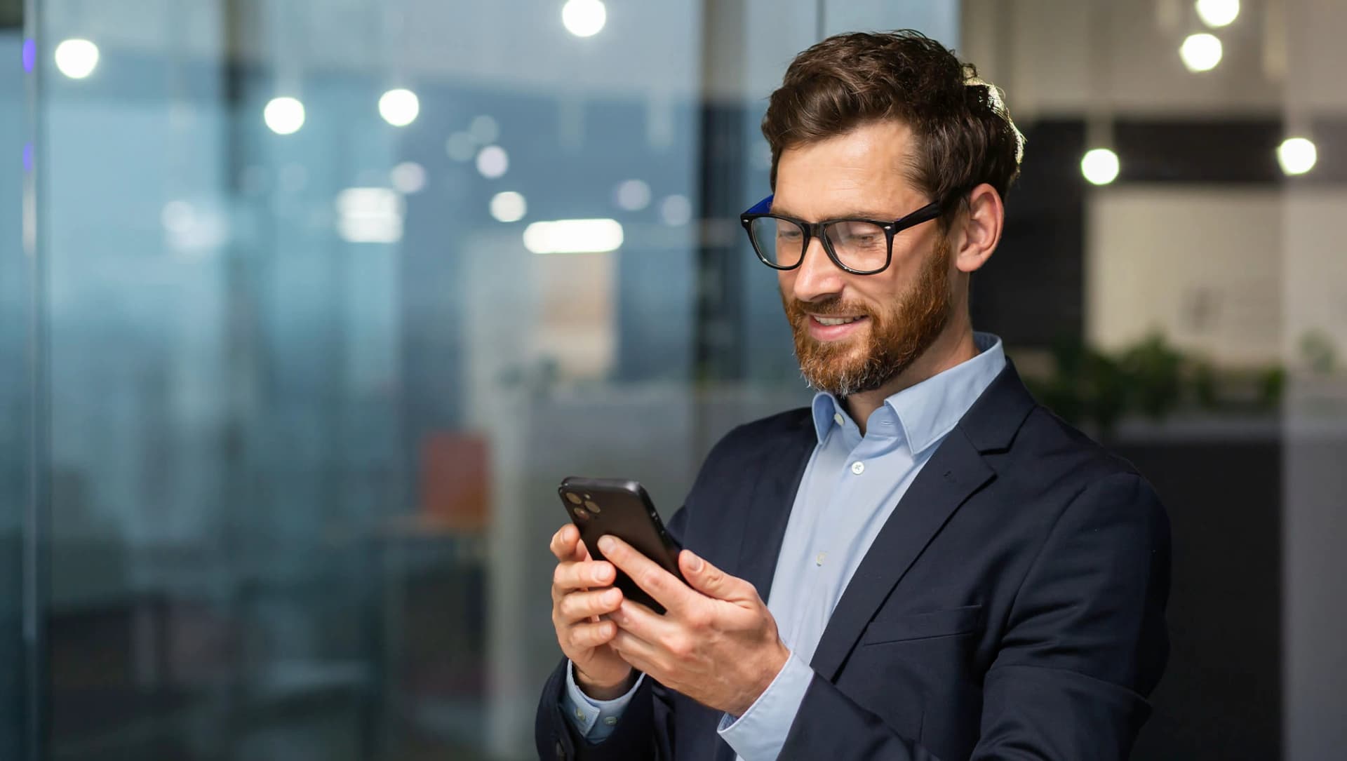 Fröhlicher Geschäftsmann blickt auf sein Handy