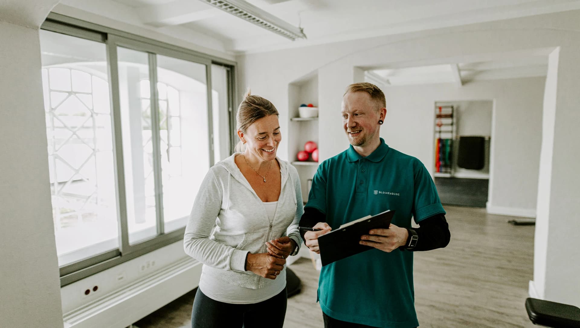 Sporttherapeut geht mit Patientin den Trainingsplan durch