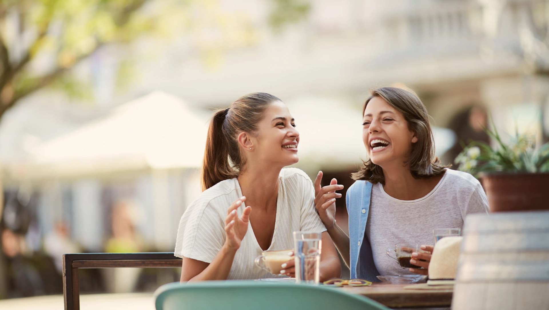Zwei Freundinnen sitzen lachend beim Essen im Restaurant